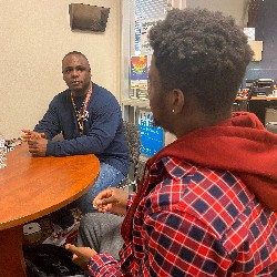 DeAngelo Nedd sits outside his office with a student